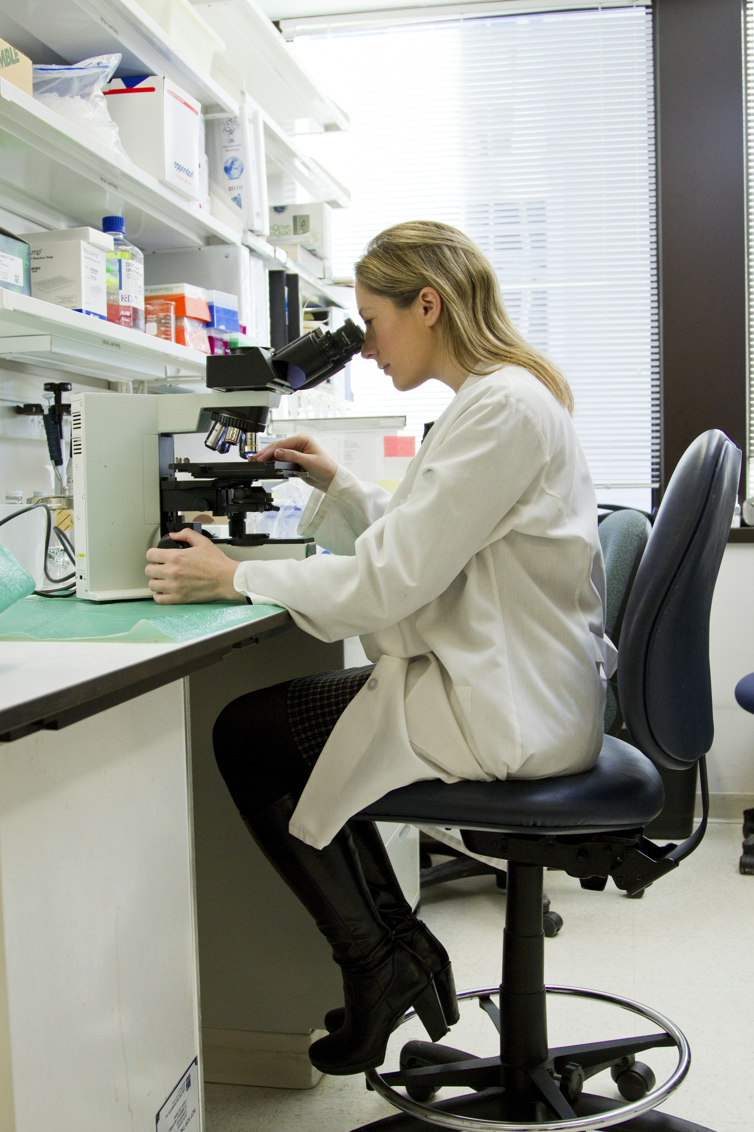 Research professional reviewing samples through a laboratory microscope