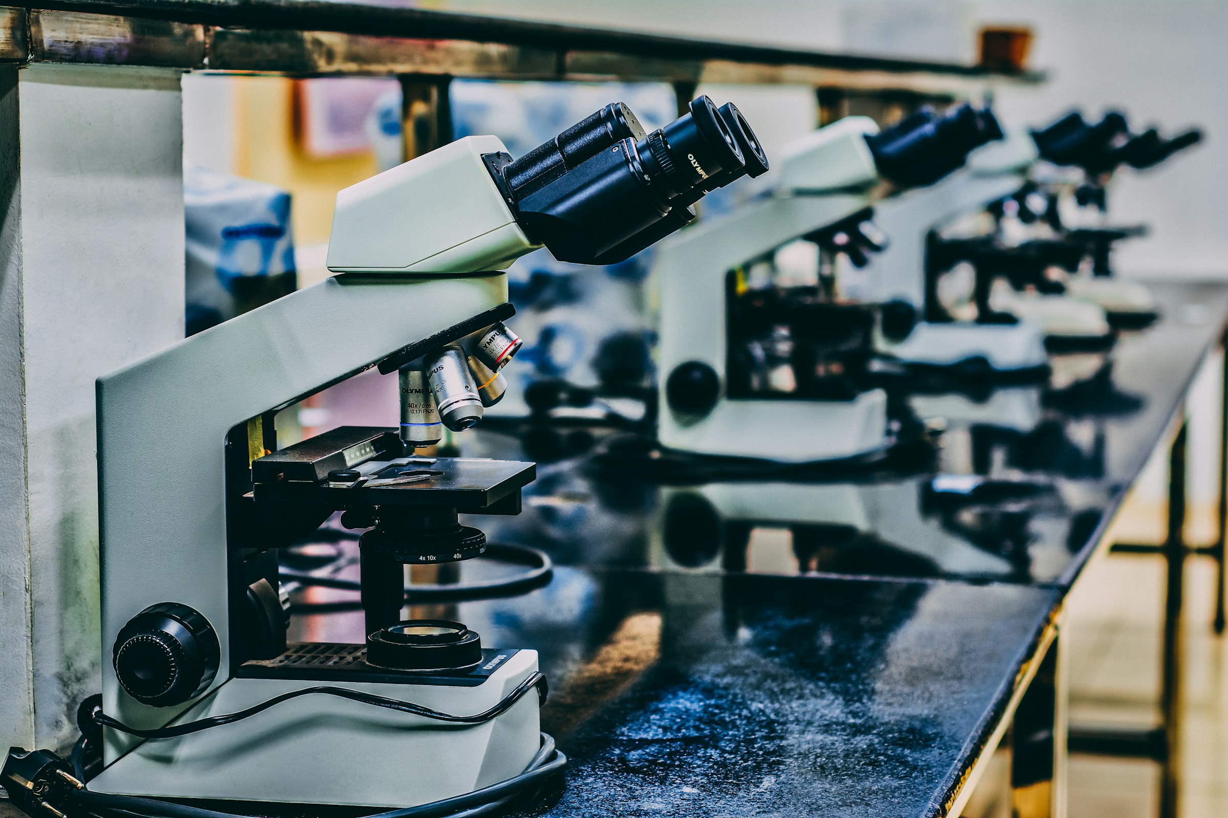 Microscopes arranged across a research laboratory bench